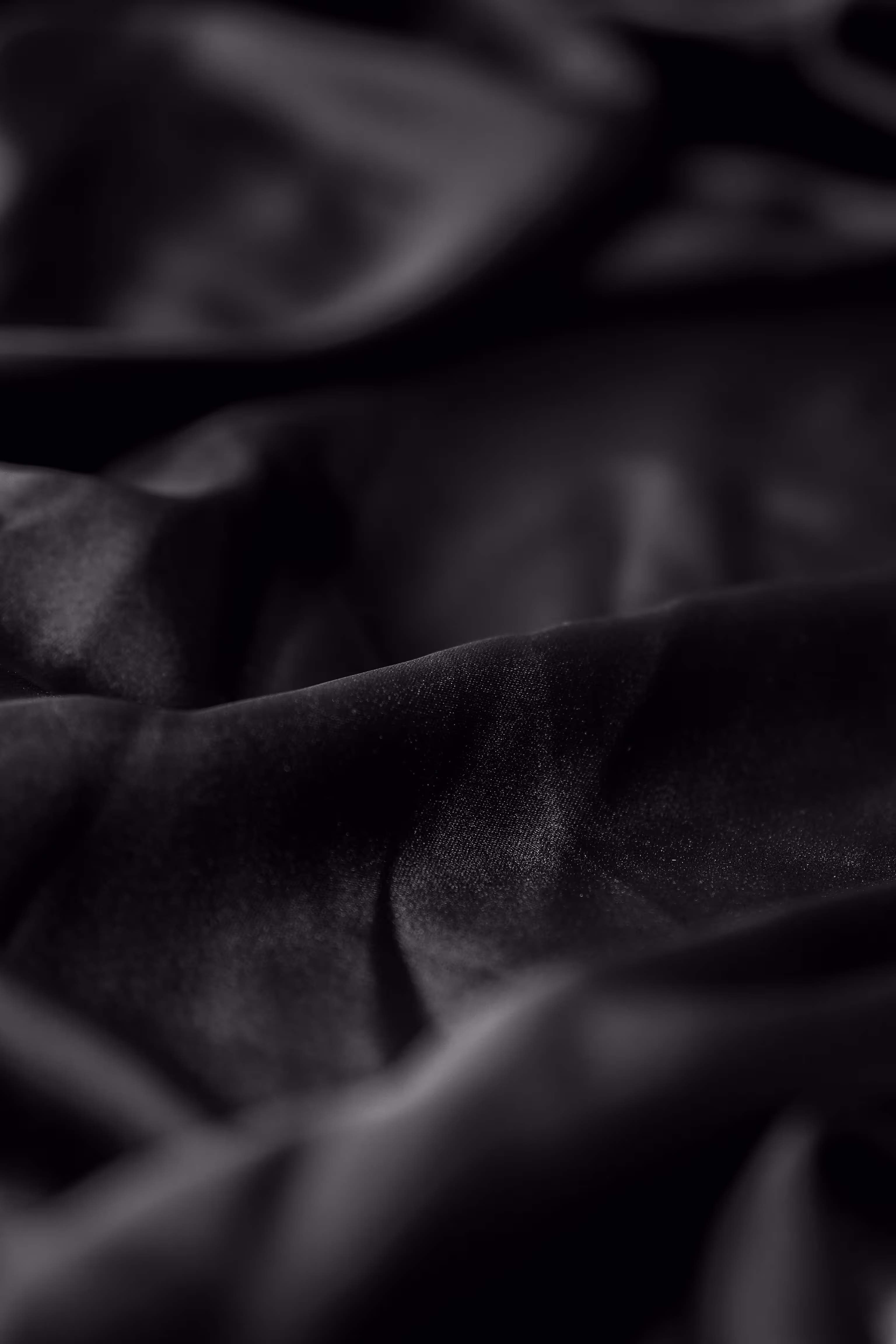 Close-up of soft black fabric with folds and shadows creating a textured appearance.